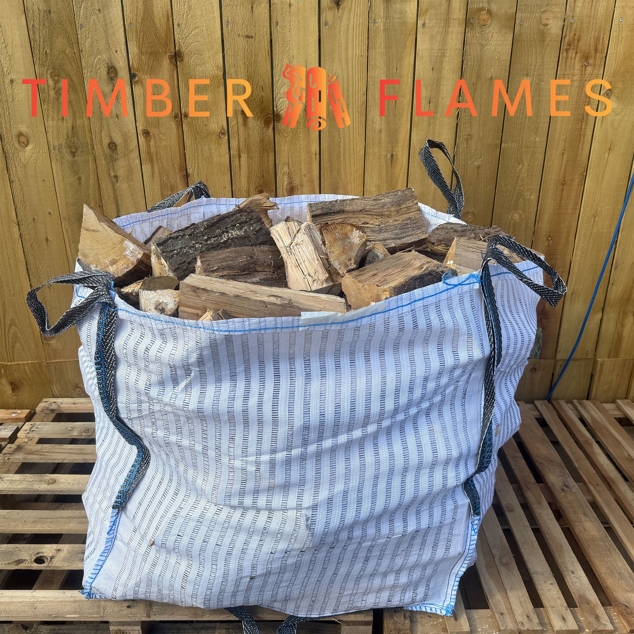 Bag of firewood labeled 'Timber Flames' on a wooden pallet.
