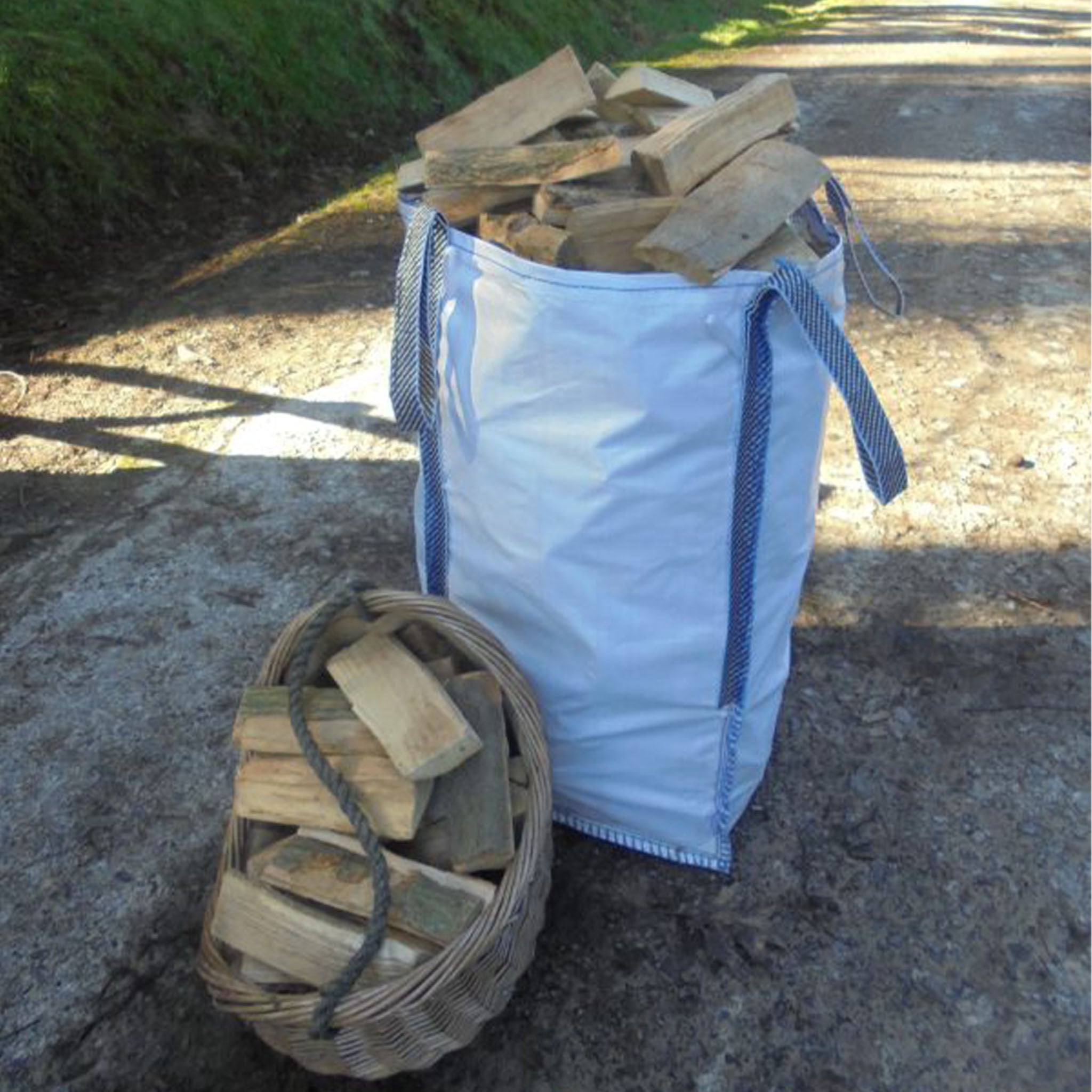 White firewood bag filled with wood next to a woven basket of wood on a stone path.